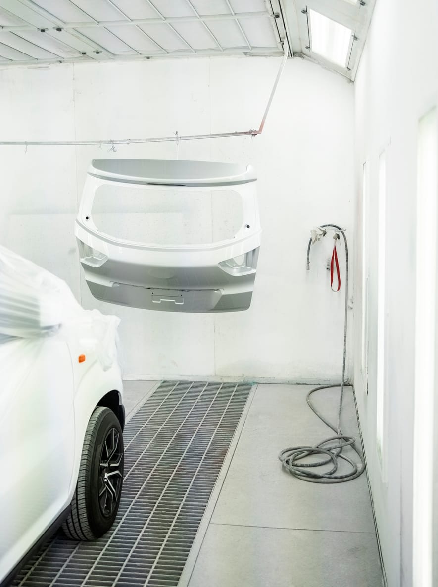 Freshly painted tailgate hanging in a downdraft spray booth