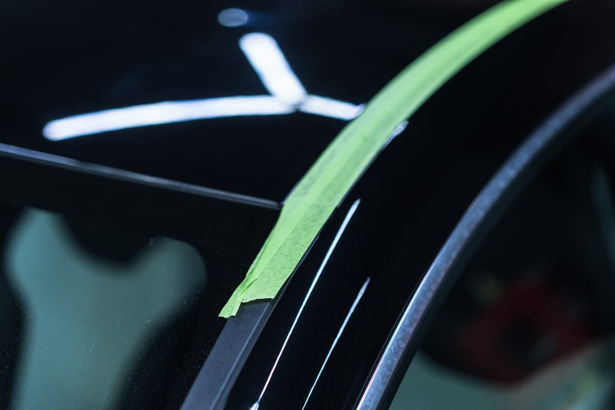 Mirror-gloss black paintwork along a masked window pillar